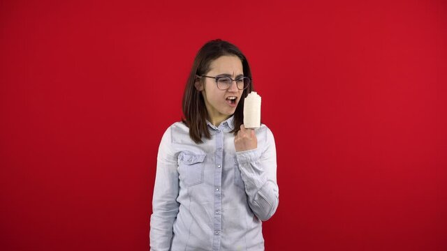 Young woman screaming with rewind bandage finger and shouts. Shooting on a red background.