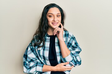 Beautiful middle eastern woman wearing casual clothes smiling looking confident at the camera with crossed arms and hand on chin. thinking positive.