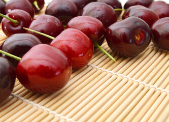 Handful of a red cherry on a bamboo mat
