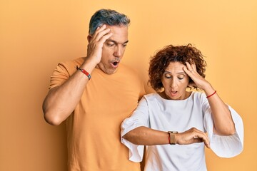 Obraz premium Beautiful middle age couple together wearing casual clothes looking at the watch time worried, afraid of getting late