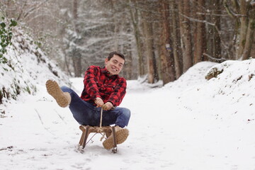 Back to childhood - Happy man riding a sleigh, having fun and laughing