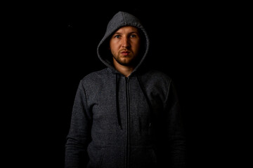 Fototapeta na wymiar Man in a hood and a hoodie on a dark background