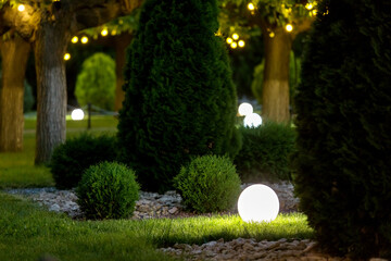 ground garden lantern with glow by electric lamp with a ball diffuser in the green grass on...