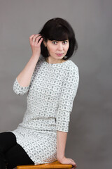Adult beautiful woman model wooden chair near gray background.