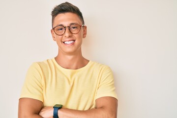 Young hispanic boy wearing casual clothes and glasses happy face smiling with crossed arms looking...