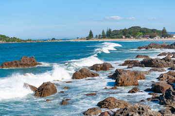 Rocky foreshore at base of Mount Maunganui with waves surging in.