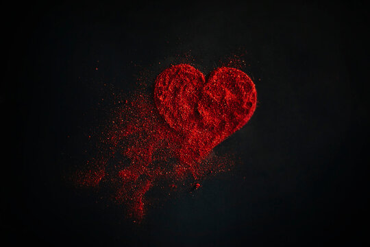 Scattered red heart made of sparkles on a black background. Shimmering dust symbol.