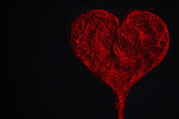 Red heart made of sequins on a black background.