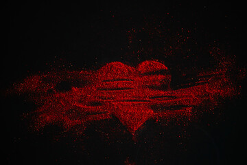 Scattered red heart made of sparkles on a black background. Shimmering dust symbol.