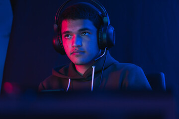 Shallow focus of a Hispanic male gamer with headphones streaming an online video game © Eduardo Sandoval/Wirestock
