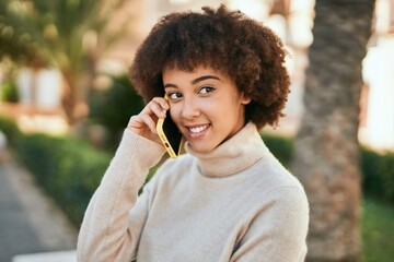 Young hispanic girl smiling happy talking on the smartphone at the park.