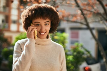 Fototapeta premium Young hispanic girl smiling happy using smartphone at the city.