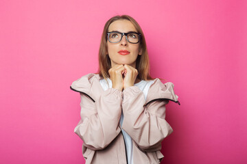 Pensive young woman in pink jacket, pink isolated background