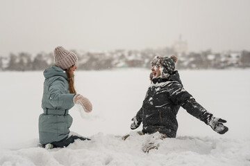 Happy couple having fun playing in snow. Snowball fight in winter