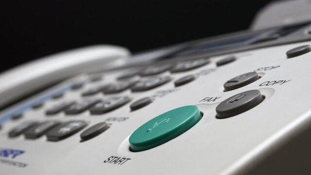 Male Finger Presses The Start Button On White Fax On Black Background.