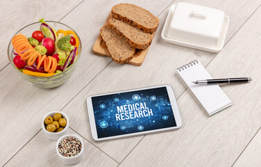 MEDICAL RESEARCH concept in tablet pc with healthy food around, top view
