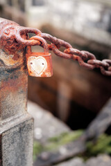 Old rusty padlock with heart shape on a metal chain, selective focus. Town folklore and legend concept.