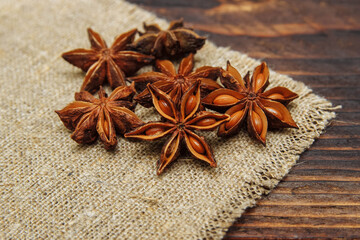 Dry seasoning anise on a linen napkin and on a brown wooden background close-up, the concept of spices and aromatic seasonings, cooking and drinks, Christmas baking