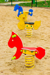 Vertical selective focus shot of spring rockers in a sandy playground