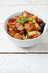 Diced cooked vegetables on light wood background in white plate. Healthy lunch - stewed garden...