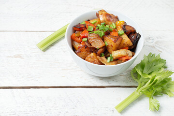 Diced cooked vegetables on light wood background in white plate. Healthy lunch - stewed garden...