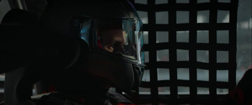 CU portrait of sports car driver closing helmet visor, starting a race on a speedway. Shot with 2x anamorphic lens