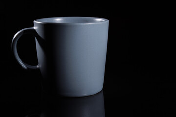 Grey ceramic cup close-up on a black background.