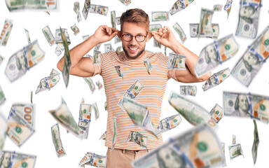 Young caucasian man wearing casual clothes and glasses smiling pulling ears with fingers, funny...