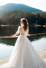 Graceful bride in luxury wedding dress near the lake. Wedding in mountains