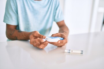 Young hispanic diabetic man measuring glucose level at home