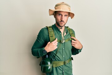 Handsome man with beard wearing explorer hat and backpack skeptic and nervous, frowning upset because of problem. negative person.
