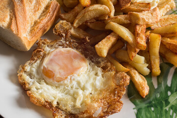 A delicious plate of fried potatoes and fried egg accompanied with a piece of bread. Traditional food.