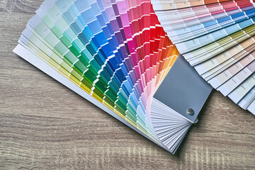 Color wheel palette for choosing paint tone. Various colors on wooden table background with copy...