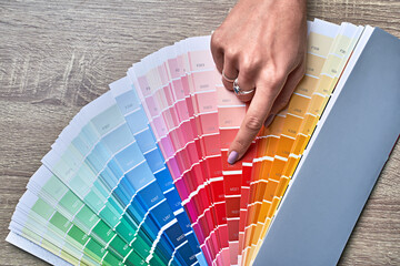 Color wheel for choosing paint tone. Hands of female interior designer working with palette for...