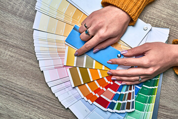 Color wheel for choosing paint tone. Hands of female interior designer working with palette for...