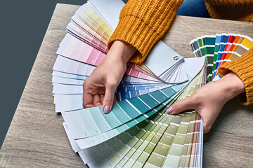 Color wheel for choosing paint tone. Hands of female interior designer working with palette for...