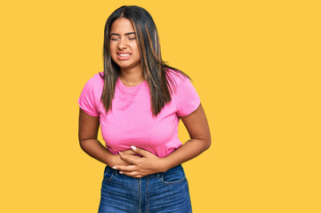 Young latin girl wearing casual clothes with hand on stomach because nausea, painful disease feeling unwell. ache concept.