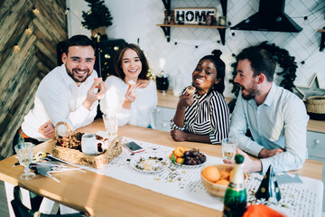 Cheerful group of friends having holiday dinner in kitchen