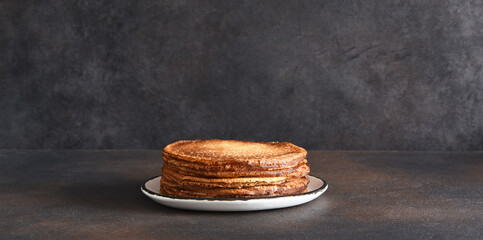 Stack of pancakes on the plate on a dark background. Thin pancakes. Good morning.