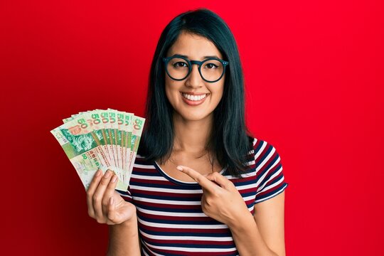 Beautiful asian young woman holding 50 hong kong dollars banknotes smiling happy pointing with hand and finger