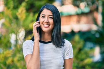 Young hispanic woman smiling happy talking on the smartphone at the city.