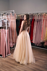 Young beautiful brunette girl wearing a full-length beige yellow champaign chiffon slit prom ball...