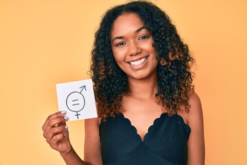 Young african american woman holding we are equal paper looking positive and happy standing and smiling with a confident smile showing teeth