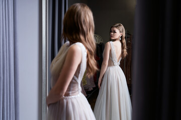 Young beautiful brunette girl wearing a full-length silver white chiffon prom ball gown decorated...