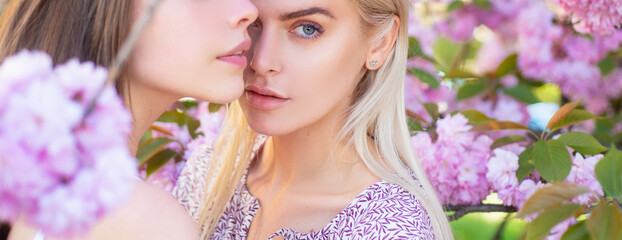 Spring girls. Outdoor close up portrait of young beautiful fashionable girl posing near blooming sakura tree with pink flowers. Baner, copy space.