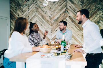 Joyful coworkers talking at table at Christmas