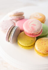 Multi-colored macarons on wood background with soft lights and shadows. Gentle macaroons on table on light background