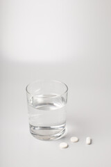 Glass of water and pills on white background