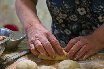 Baker makes  small meat pied. Raw dough balls on wooden board.