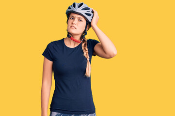 Beautiful caucasian woman wearing bike helmet confuse and wonder about question. uncertain with doubt, thinking with hand on head. pensive concept.